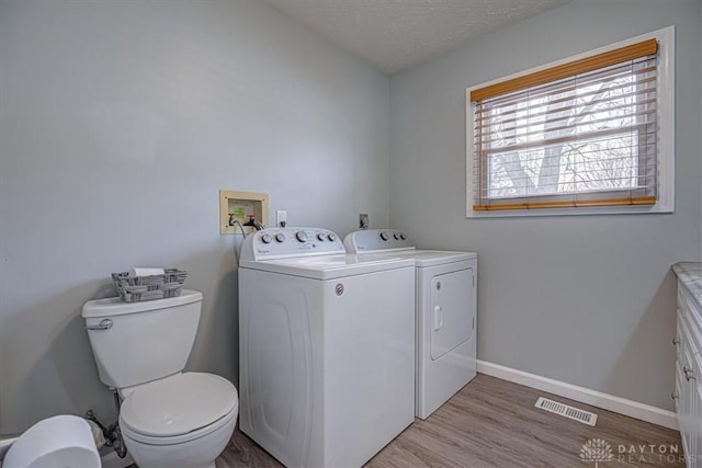 washroom with washer and dryer, a textured ceiling, and light hardwood / wood-style floors