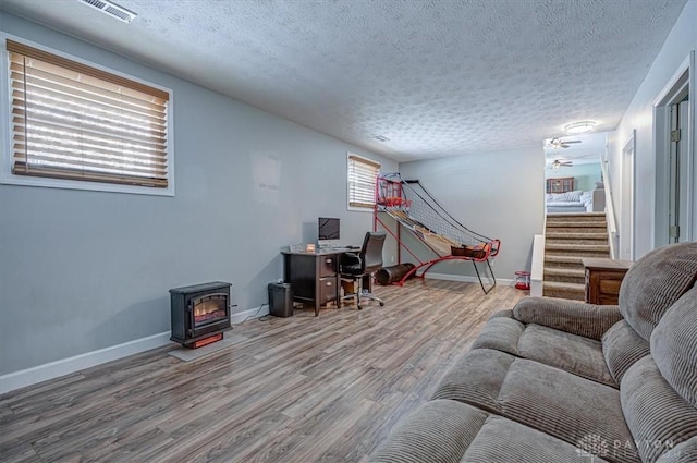 office featuring hardwood / wood-style flooring, a textured ceiling, and a wood stove