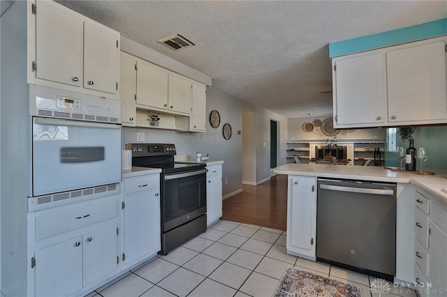 kitchen featuring light tile patterned flooring, stainless steel appliances, a textured ceiling, and white cabinets