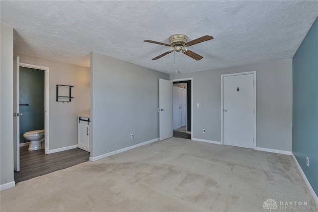 unfurnished bedroom with light carpet, a closet, ceiling fan, and ensuite bathroom