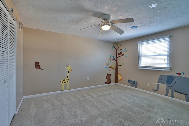 unfurnished bedroom featuring light colored carpet, a textured ceiling, ceiling fan, and a closet