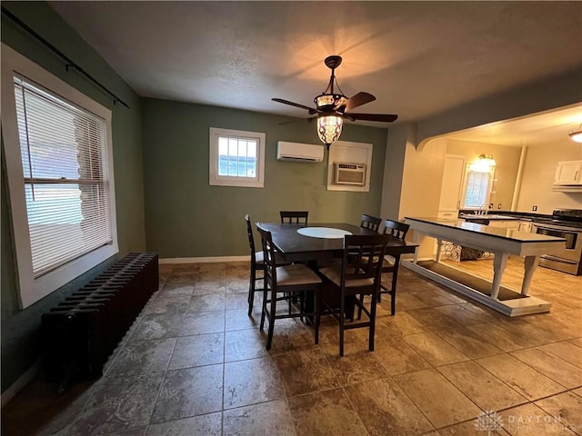 dining space with ceiling fan and an AC wall unit