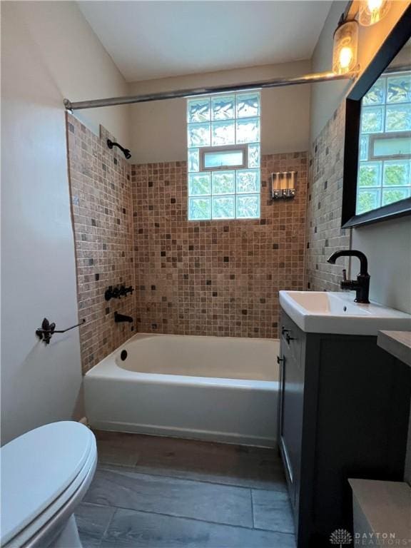 full bathroom featuring vanity, tiled shower / bath, and toilet