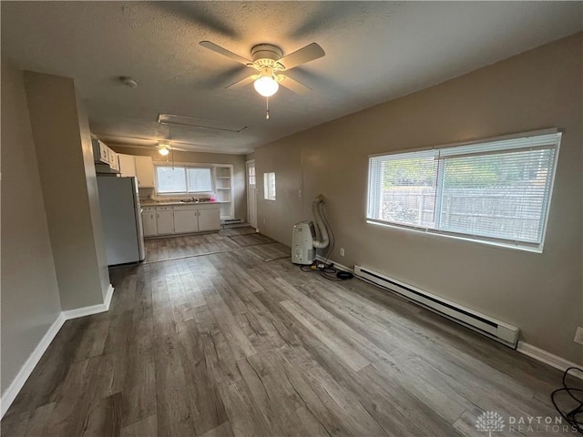 unfurnished living room featuring a baseboard radiator, plenty of natural light, and light wood-type flooring