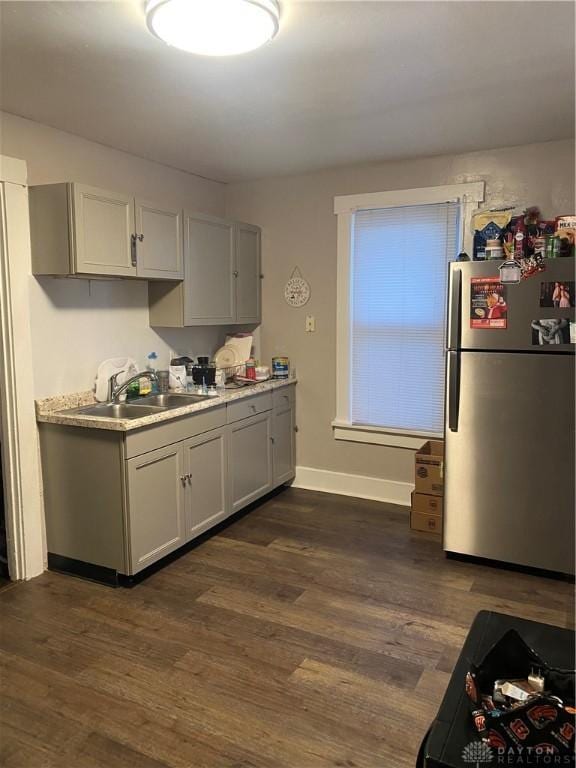 kitchen with dark hardwood / wood-style floors, sink, gray cabinetry, and stainless steel refrigerator