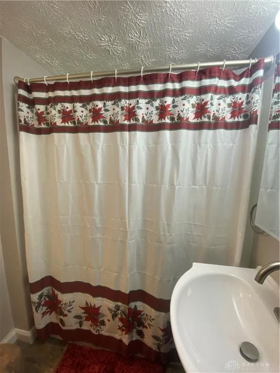 bathroom with a shower with shower curtain, sink, and a textured ceiling