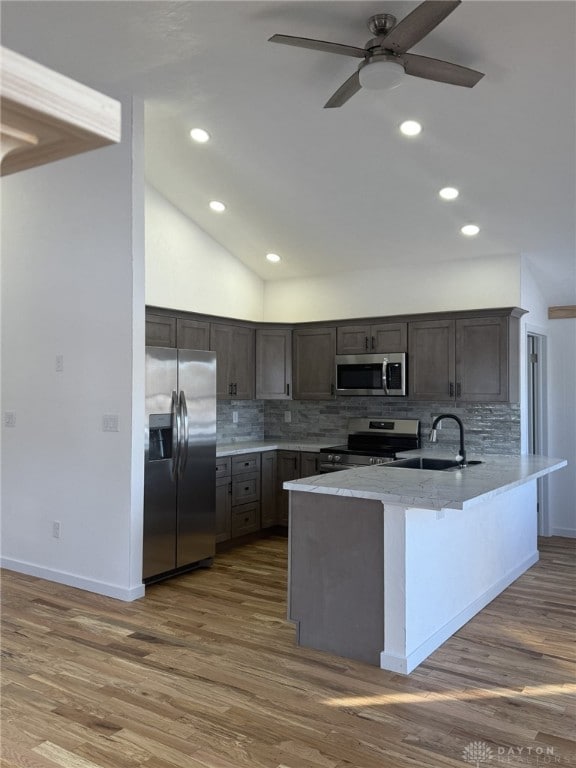 kitchen with sink, stainless steel appliances, dark hardwood / wood-style flooring, decorative backsplash, and kitchen peninsula