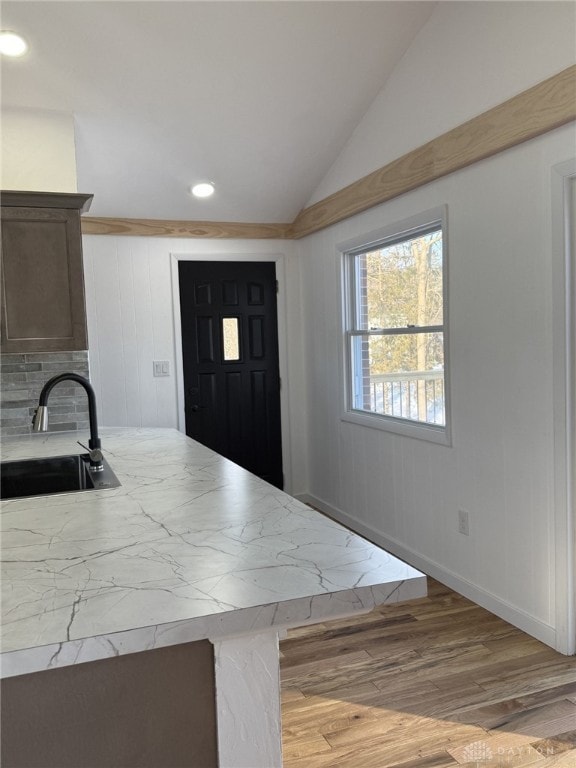 kitchen with vaulted ceiling, light hardwood / wood-style floors, and sink