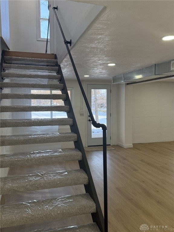 stairway with wood-type flooring and a textured ceiling