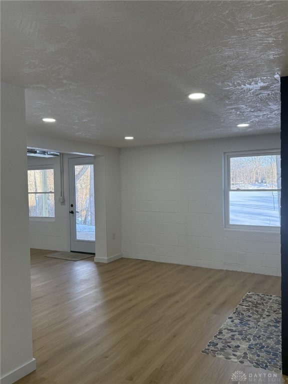 unfurnished room with wood-type flooring, a wealth of natural light, and a textured ceiling