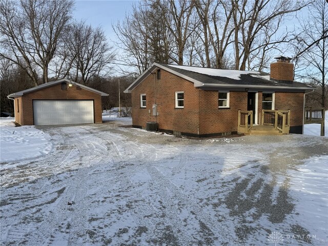 view of snowy exterior with an outbuilding and a garage