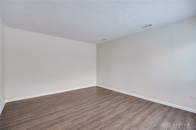 spare room featuring dark hardwood / wood-style floors and a textured ceiling