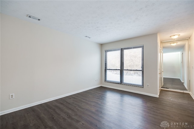 unfurnished room with dark wood-type flooring and a textured ceiling