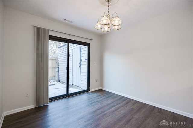 empty room featuring a notable chandelier and dark hardwood / wood-style flooring