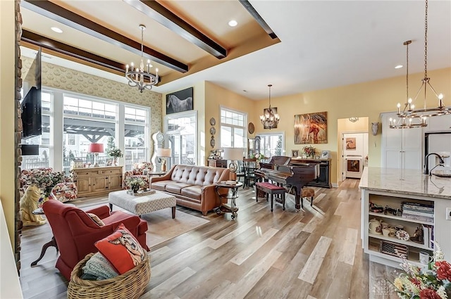 living room with beamed ceiling, sink, an inviting chandelier, and light hardwood / wood-style floors