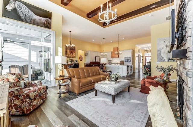 living room featuring a stone fireplace, dark hardwood / wood-style floors, and a chandelier