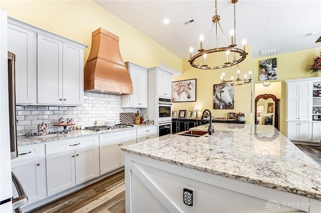 kitchen with white cabinetry, decorative light fixtures, custom exhaust hood, and stainless steel gas cooktop