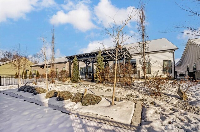 snow covered back of property featuring a pergola