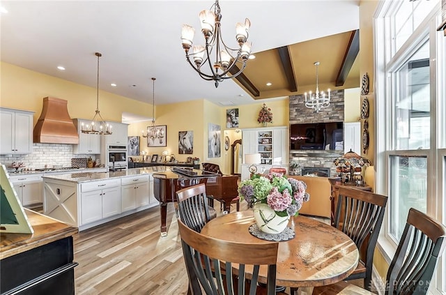 dining space featuring an inviting chandelier, beam ceiling, and light hardwood / wood-style flooring