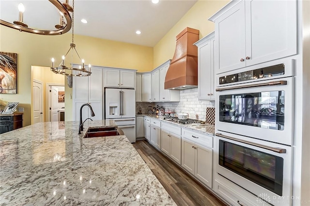 kitchen with premium range hood, light stone countertops, white cabinets, and white appliances