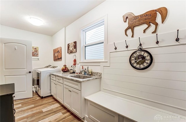 washroom featuring cabinets, washing machine and dryer, sink, and light hardwood / wood-style floors