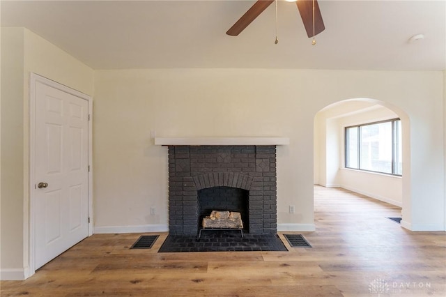 unfurnished living room with a brick fireplace, hardwood / wood-style floors, and ceiling fan