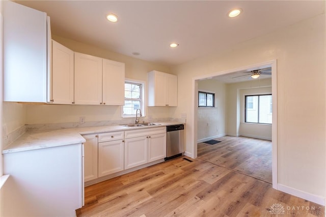 kitchen featuring sink, light hardwood / wood-style flooring, stainless steel dishwasher, ceiling fan, and white cabinets