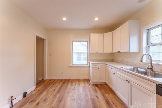 kitchen with dishwasher, white cabinetry, sink, and light hardwood / wood-style floors