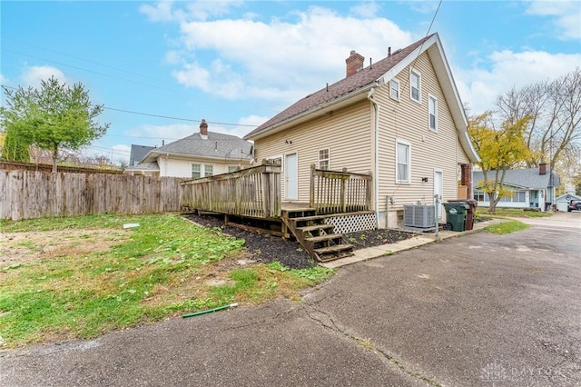 back of property with a wooden deck, central AC, and a lawn