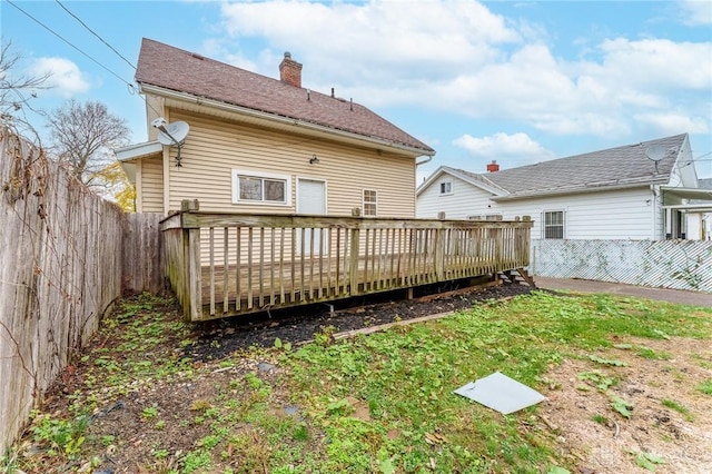 rear view of property featuring a wooden deck and a lawn