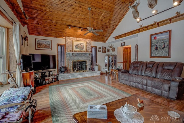 living room featuring high vaulted ceiling, a fireplace, ceiling fan, wooden ceiling, and light wood-type flooring