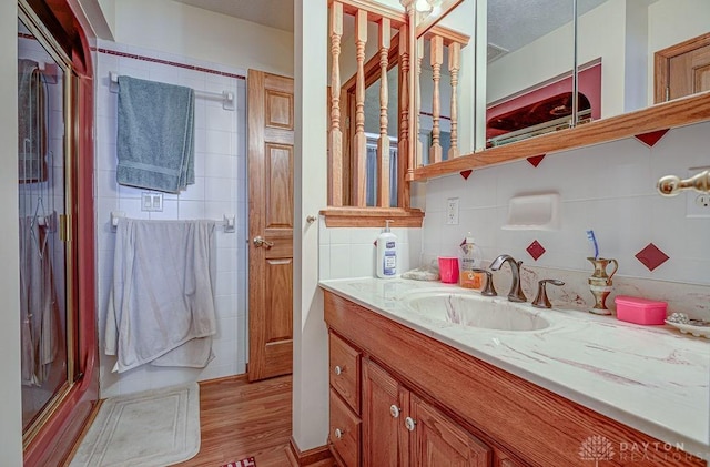 bathroom with vanity, tasteful backsplash, wood-type flooring, and walk in shower