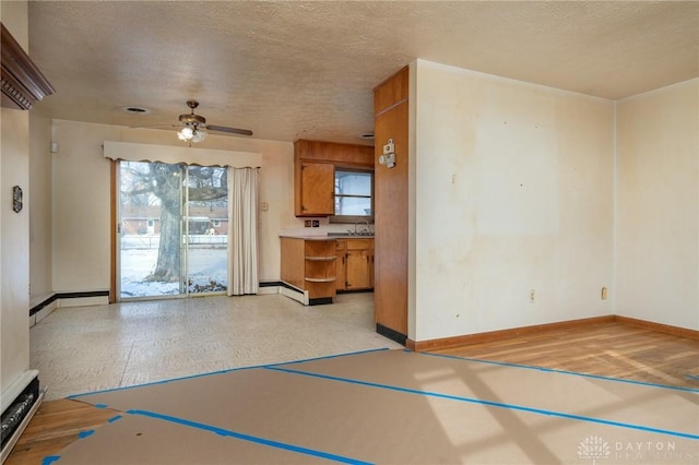 interior space featuring ceiling fan, sink, a textured ceiling, and a baseboard heating unit