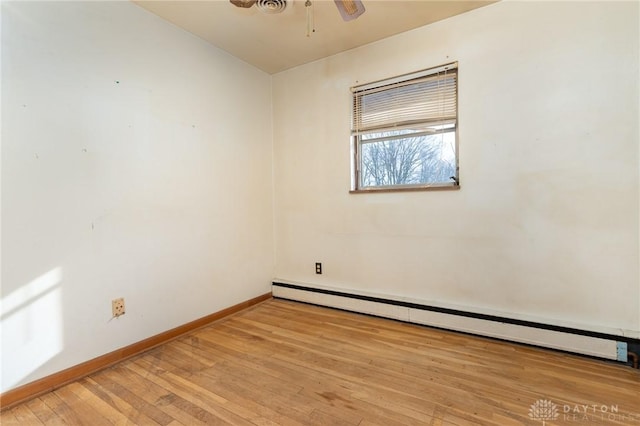 empty room with ceiling fan, a baseboard heating unit, and light wood-type flooring