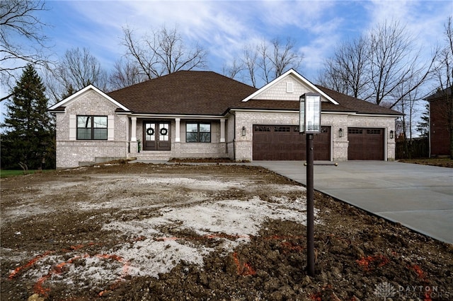 view of front of house with brick siding, roof with shingles, french doors, driveway, and an attached garage