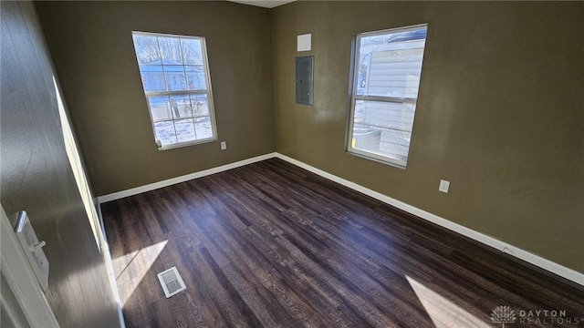 unfurnished room featuring dark wood-type flooring, a healthy amount of sunlight, and electric panel