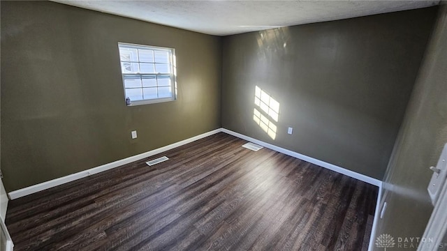 spare room with dark hardwood / wood-style flooring and a textured ceiling