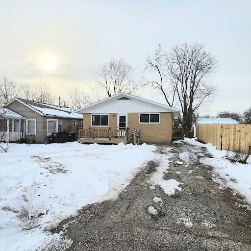 snow covered back of property with a wooden deck