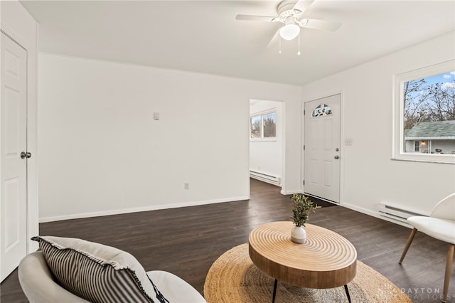 living room featuring baseboard heating, ceiling fan, and dark wood-type flooring