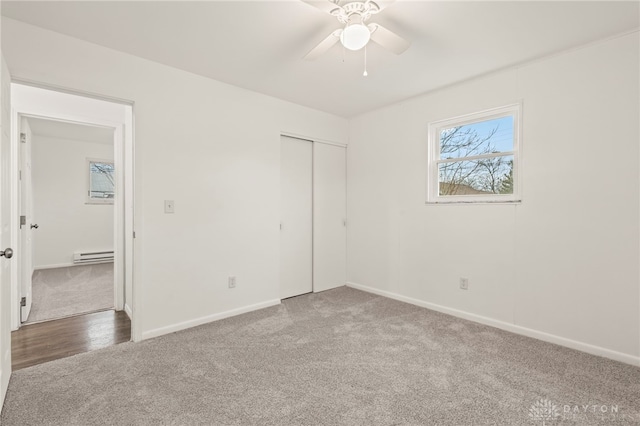 unfurnished bedroom featuring carpet, a closet, ceiling fan, and baseboard heating