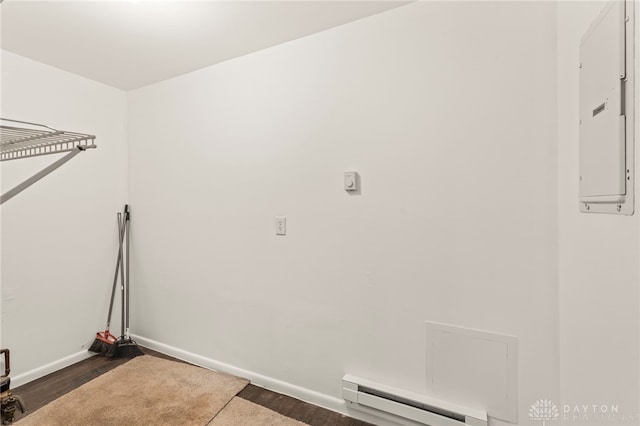 laundry area with a baseboard heating unit, dark wood-type flooring, and electric panel