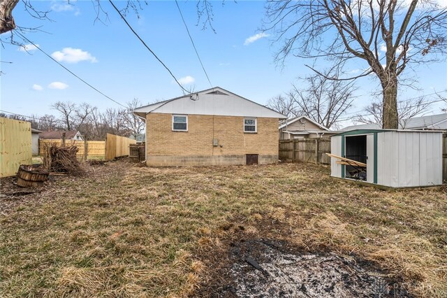 back of property featuring a lawn and a storage unit