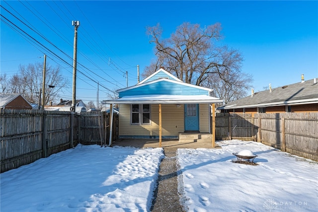 snow covered back of property featuring a fire pit