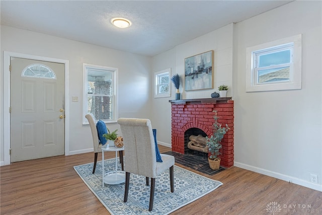 dining area with hardwood / wood-style flooring, a brick fireplace, and a textured ceiling