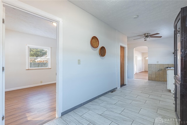 hall with light hardwood / wood-style flooring and a textured ceiling