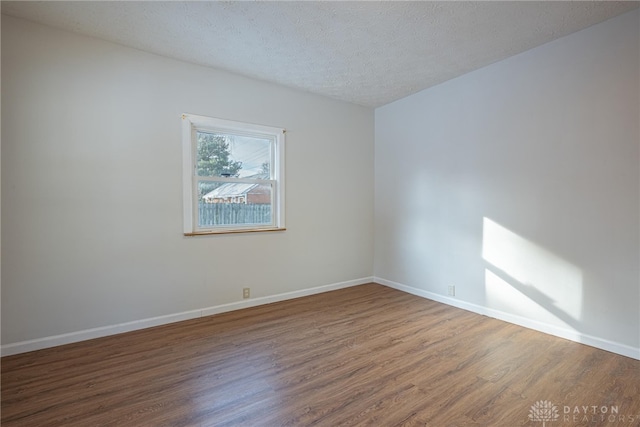 empty room with wood-type flooring and a textured ceiling