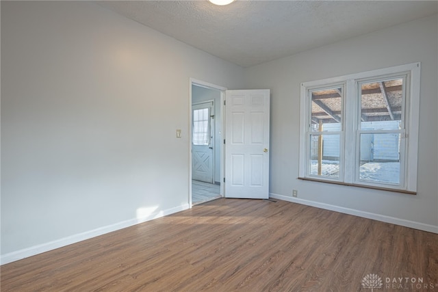 empty room with a healthy amount of sunlight, wood-type flooring, and a textured ceiling