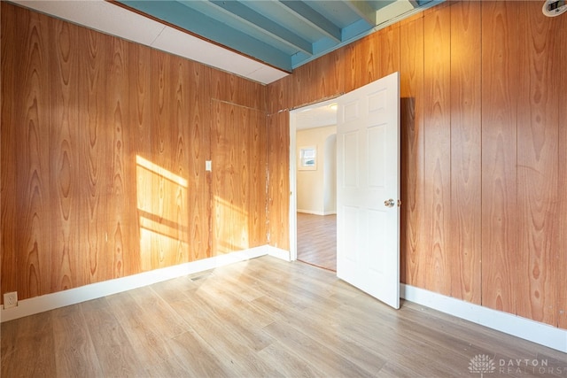 unfurnished room featuring beamed ceiling, wood-type flooring, and wood walls