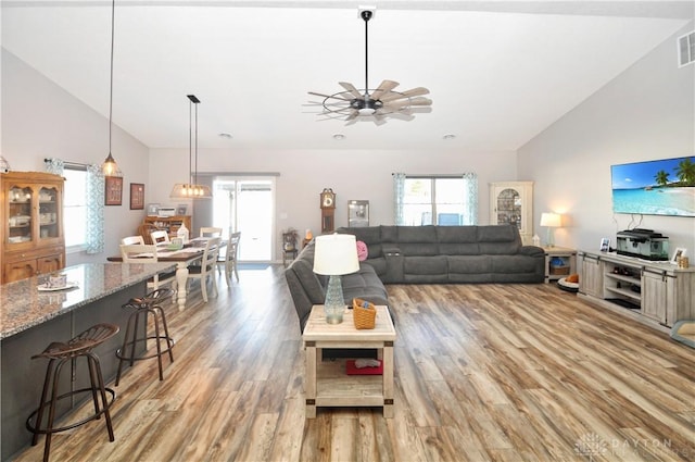 living room featuring ceiling fan, lofted ceiling, and light wood-type flooring