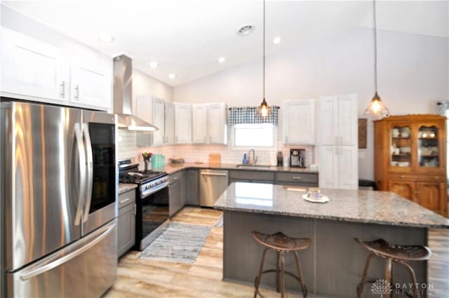 kitchen with gray cabinetry, wall chimney range hood, stainless steel appliances, and a center island